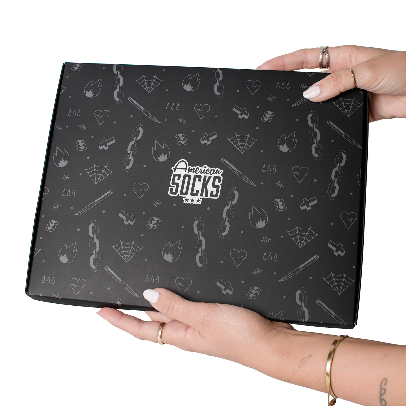 Hands holding up black tattoo inspired giftbox by american socks